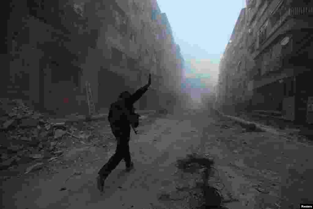 A rebel fighter gestures as he runs across a street during what the rebel fighters said was an offensive against them by Syrian government forces in the Mleha suburb of Damascus. (Reuters/Bassam Khabieh&nbsp;)