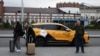 Njerëz duke qëndruar pranë një veture të Yandex Taxi, në një rrugë të Moskës.