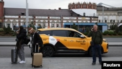 Njerëz duke qëndruar pranë një veture të Yandex Taxi, në një rrugë të Moskës.