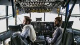 AFGHANISTAN -- Taliban fighters sit in the cockpit of an Afghan Air Force aircraft at the airport in Kabul, August 31, 2021