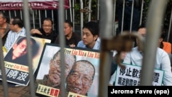 Активисты из Гонконгского альянса в поддержку патриотических демократических движений Китая держат фотографии китайского диссидента и лауреата Нобелевской премии мира Лю Сяобо во время митинга у Китайского офиса связи в Гонконге, Китай, 10 июля 2017 года