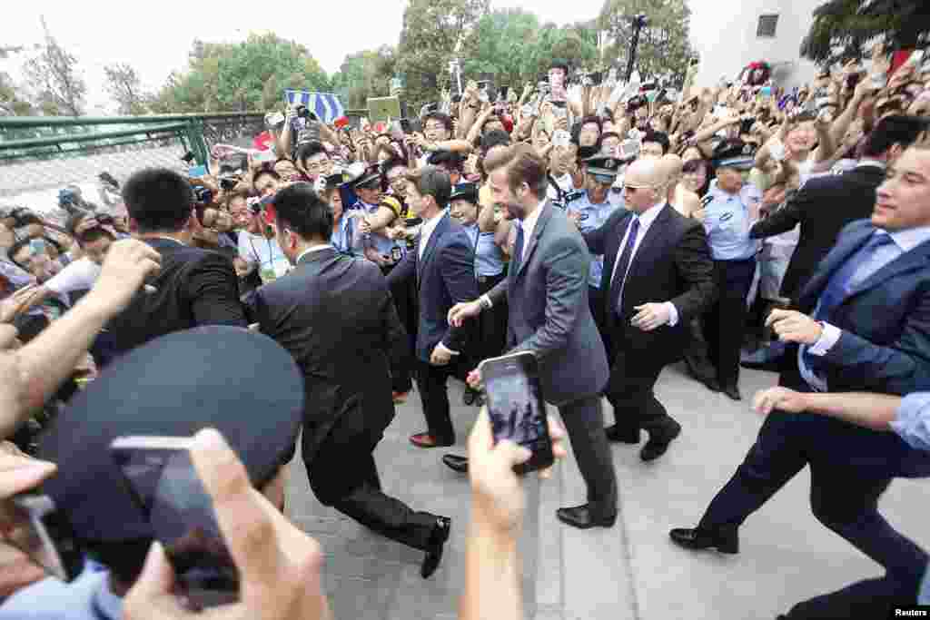 Fans push toward policemen as they take pictures and videos of former England soccer captain David Beckham upon his arrival at Tongji University in Shanghai. (Reuters/Stringer)