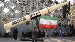 Iranians stand next to a mockup of a Kheibar missile in Tehran amid a fragile cease-fire in the Middle East. 