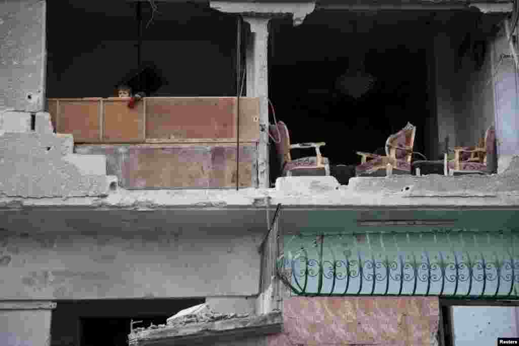 Two days before the attacks, a boy peeks from the ruins of a damaged house.