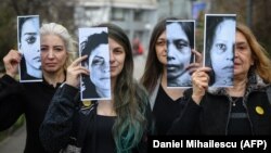 Disa aktiviste për të drejtat e grave mbajnë në duar fotografi të viktimave të dhunës në familje. Rumani 2020.