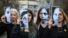 Disa aktiviste për të drejtat e grave mbajnë në duar fotografi të viktimave të dhunës në familje. Rumani 2020.
