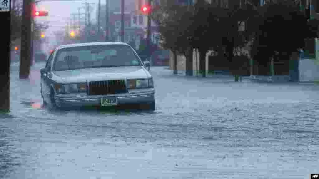 A car sits in a flooded street near the ocean ahead of Hurricane Sandy in Atlantic City, New Jersey.