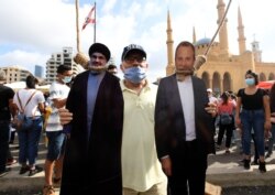 Demonstrant u Bejrutu sa fotografijama Hasana Nasralaha (L), vođe šiitskog libanskog pokreta Hezbolah i bivšeg ministra vanjskih poslova Gibrana Basila, 8. avgust 2020.