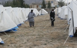 FILE: Men with face masks spray near tents used as a quarantine facility in Balochistan.