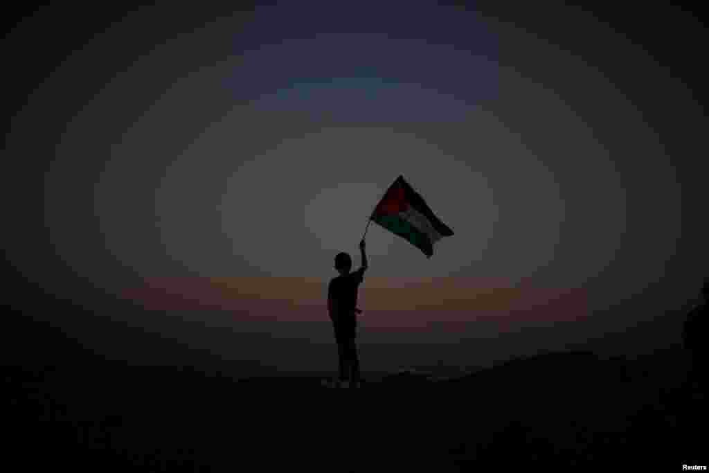 A boy waves a Palestinian flag at the Israel-Gaza border amid heightened tensions after deadly clashes involving Israeli troops and protesters. (Reuters/Mohammed Salem)