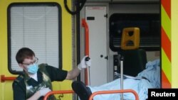 Bolničar iznosi pacijenta iz ambulantnih kola u Velikoj Britaniji