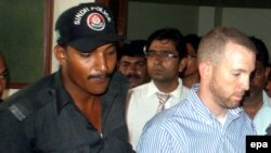 Pakistani police escort Joel Cox (right) to court in Karachi on May 6.