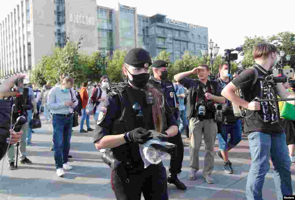 Сотрудница полиции в Москве раздает защитные маски протестующим, которые вышли на пикет против путинских поправок