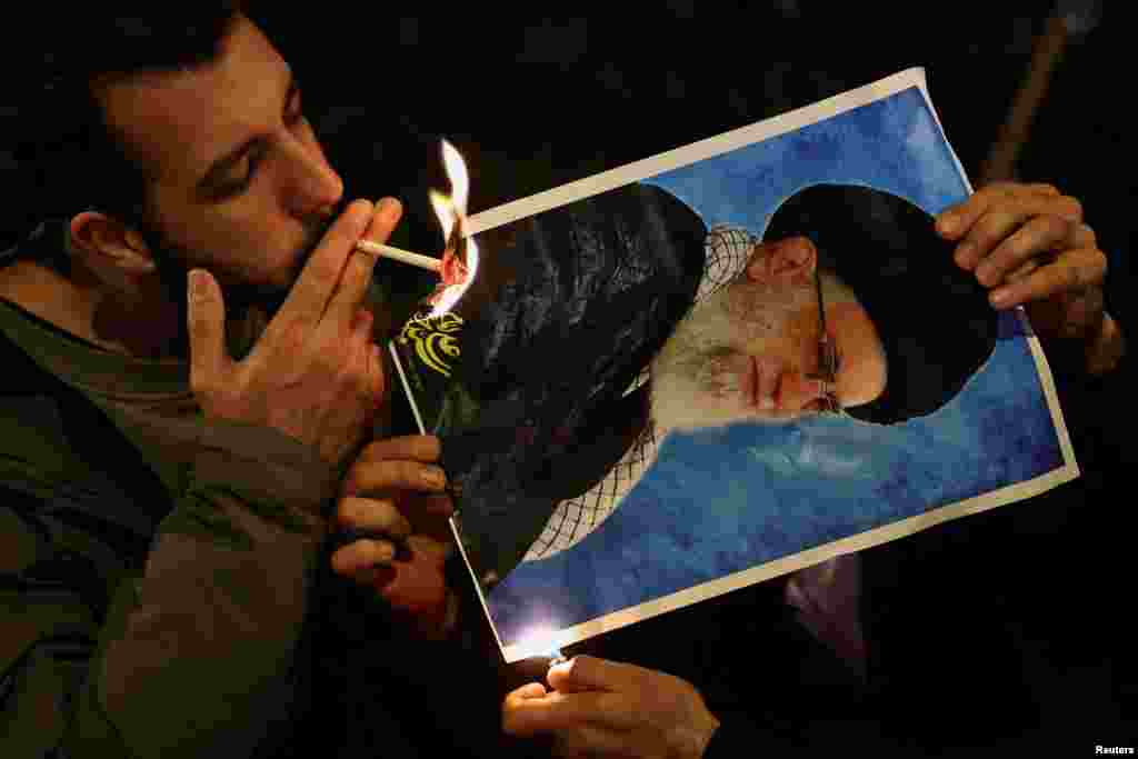 Демонстрант зажигает сигарету огнем от горящей фотографии верховного лидера Ирана аятоллы Али Хаменеи перед иранским посольством, Лондон, Великобритания, 12 января 2026 года. REUTERS/Toby Melville 