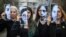 Disa aktiviste për të drejtat e grave mbajnë në duar fotografi të viktimave të dhunës në familje. Rumani 2020.