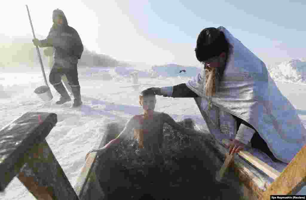 A boy takes a dip in the freezing waters of Lake Buzim during Orthodox Epiphany celebrations with the air temperature at about minus 40 degrees Celsius, near the village of Sukhobuzimskoye, north of Krasnoyarsk, Russia. (Reuters/Ilya Naymushin)