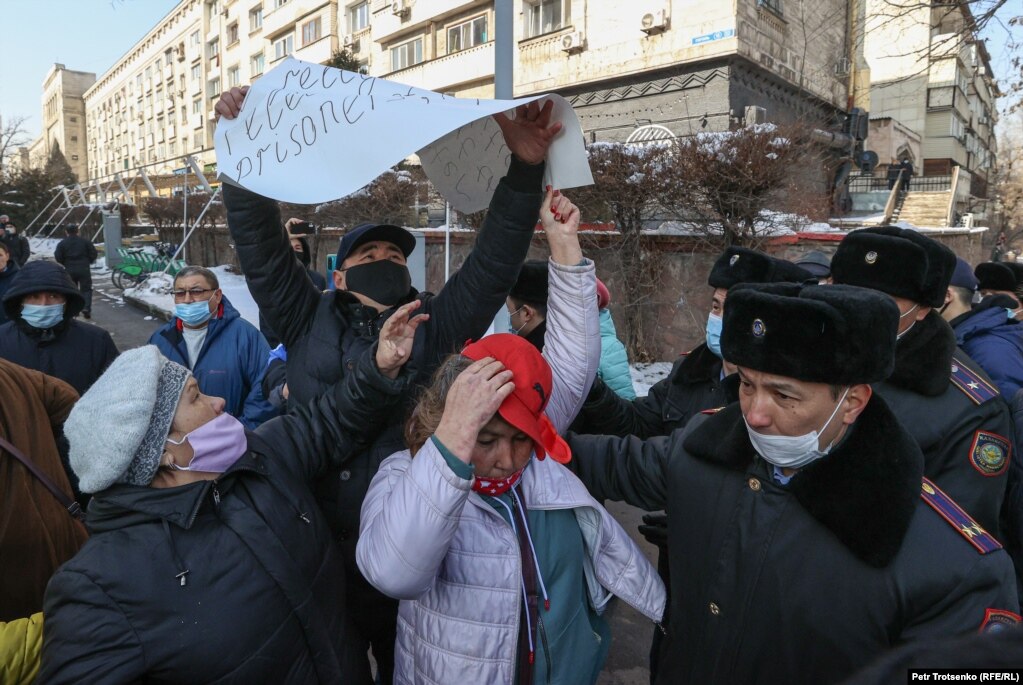 Сотрудник полиции вырывает плакат у митингующих женщин. Алматы, 28 февраля 2021 года.
