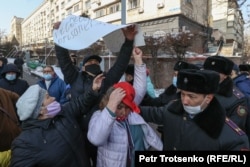 Сотрудник полиции вырывает плакат у митингующих женщин. Алматы, 28 февраля 2021 года.