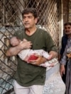 A man carries a wounded girl after an explosion in downtown Tehran on June 15 amid Israeli strikes on targets throughout Iran.