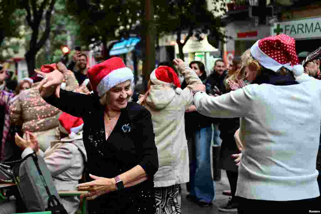 Vizitatori dansează la tradiționalul târg de Crăciun din Plaza Mayor, Madrid, în timpul aglomerației de seară, pe 14 decembrie 2025.