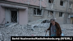 Жінка похилого віку на вулиці, засипаній уламками зрунованих російською ракетою будинків. Київ, 2 липня 2026 року