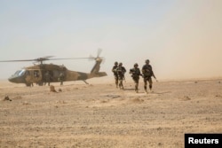 Afghan National Army 215th Corps troops disembark an Afghan Air Force Black Hawk helicopter.