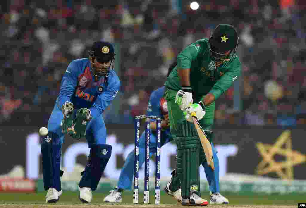 India's captain Mahendra Singh Dhoni (L) and teammate Suresh Raina (C) look on as Pakistan's Sharjeel Khan (R) plays a shot during the World T20 cricket tournament match between India and Pakistan at The Eden Gardens Cricket Stadium in Kolkata on March 19