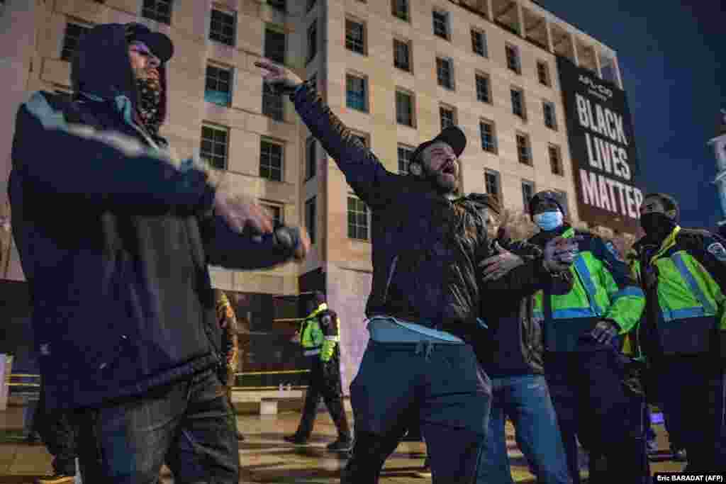 Офіцери поліції Вашингтонського метро (праворуч) відокремлюють прихильників президента США Дональда Трампа (зліва) від активістів Black Live Matters (немає на фото), позаяк люди обмінюються образами на площі Black Live Matters позаду будівлі Білого дому у Вашингтоні, округ Колумбія, США, 5 січня 2021 року