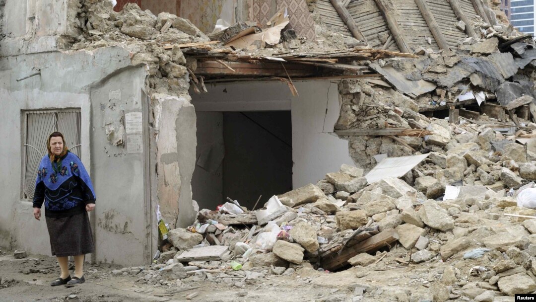 A woman stands near a demolished house in Baku. Critics say the government has trampled on people's rights in razing homes for the Crystal Hall..