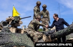 Ambasadorul SUA în Polonia, Marek Brzezinski (dreapta), strânge mâna soldaților americani aflați pe un tanc, în timp ce trupe din Polonia, SUA, Franța și Suedia participă la exercițiul militar DEFENDER-Europe 22, la Nowogrod, mai 2022.