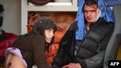 Two people sit in an ambulance waiting to be treated after a rocket slammed into a shopping mall in Donetsk's Kubishevski district on October 8.