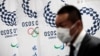 Токио олимпиадасы эмблемасының жанына өтіп бара жатқан маскадағы адам. Токио, 2020 жылдың наурызы. 