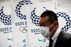 Журналіст у захисній масці під час брифінгу в оргкомітеті Токійської Олімпіади, на якому говорилось про поширення коронавірусу. 11 березня 2020 року