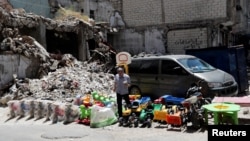 Мужчина продает детские игрушки на фоне руин разрушенных зданий в городе Идлиб. 25 мая, 2019