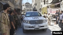Syria - Free Syrian Army fighters and residents gather around a convoy of U.N. vehicles carrying a team of United Nations chemical weapons experts at one of the sites of an alleged chemical weapons attack in Damascus' suburbs of Zamalka August 28, 2013