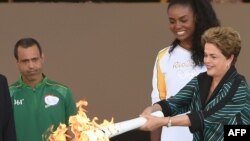 Президент Бразилии Дилма Руссефф (справа) вручает олимпийский факел бразильскому волейболисту Фабиану Клаудио во Дворце Планалто, 3 мая 2016 года.