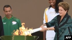 Президент Бразилії Ділма Руссеф (п) тримає олімпійський факел перед початком його подорожі містами країни, 3 травня 2016 року
