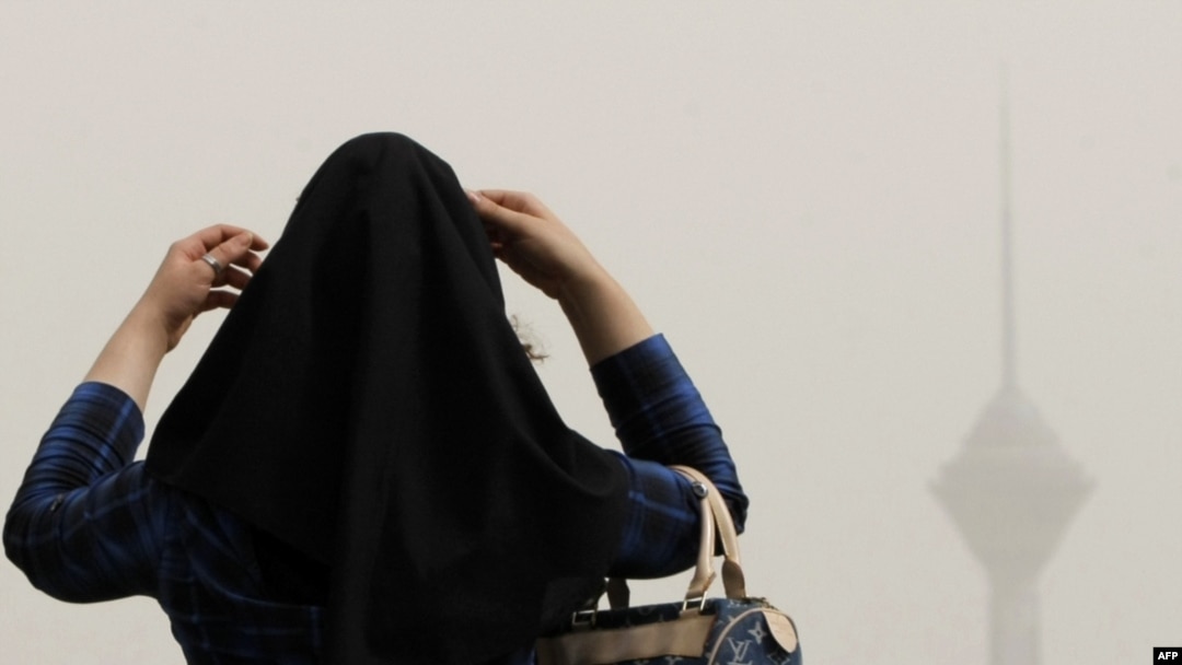 A woman adjusts her head scarf as haze settles over Tehran on July 7.