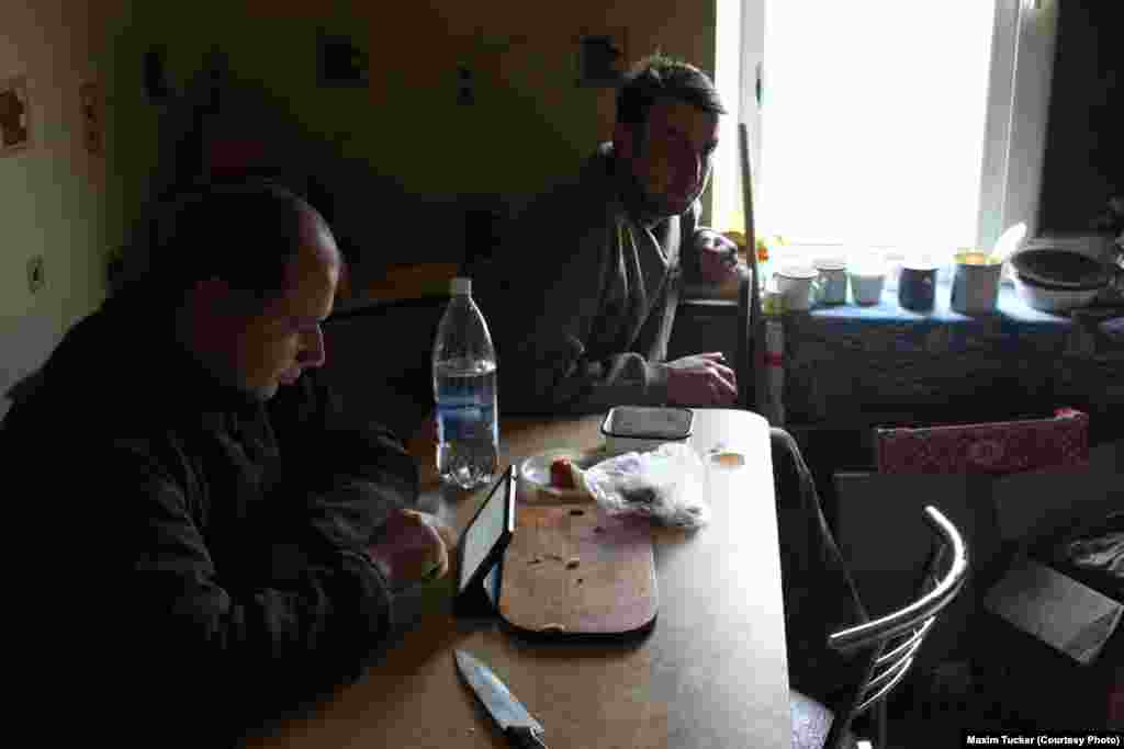 Viktor (left) and Vova take a break from the fighting at a command post in Pisky. Viktor has been fighting for less than a month, while Vova is expecting demobilization after serving a 14-month tour. &nbsp;April 3, 2016