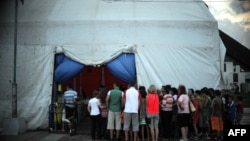 Qytetarë myslimanë të Kosovës duke pritur para një tende, për të qenë pjesë e një iftari pa pagesë, gjatë muajit të Ramazanit ( Prishtinë, 2013) 