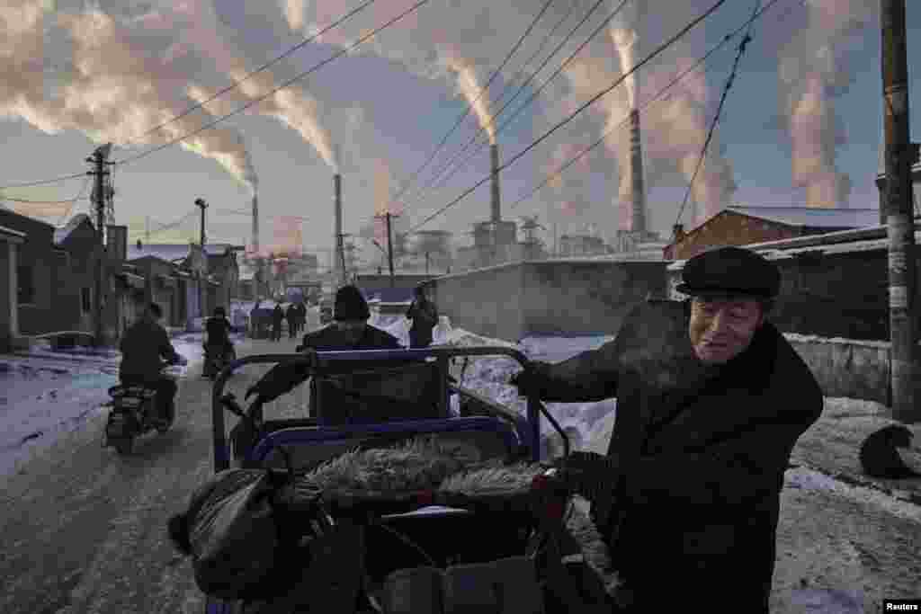 First Prize Singles in the Daily Life category was won by Getty Images&#39; Kevin Frayer. Chinese men pull a tricycle in a neighborhood next to a coal-fired power plant in Shanxi, China. (November 26, 2015)