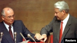 Russian President Boris Yeltsin (right) and Soviet President Mikhail Gorbachev touch hands during Gorbachev's address to the extraordinary meeting of the Supreme Soviet of the Russian Federation in Moscow in August 1991.