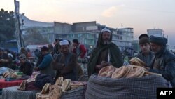 Afghan vendors wait for customers at a busy market on a cold day in Kabul on November 19.