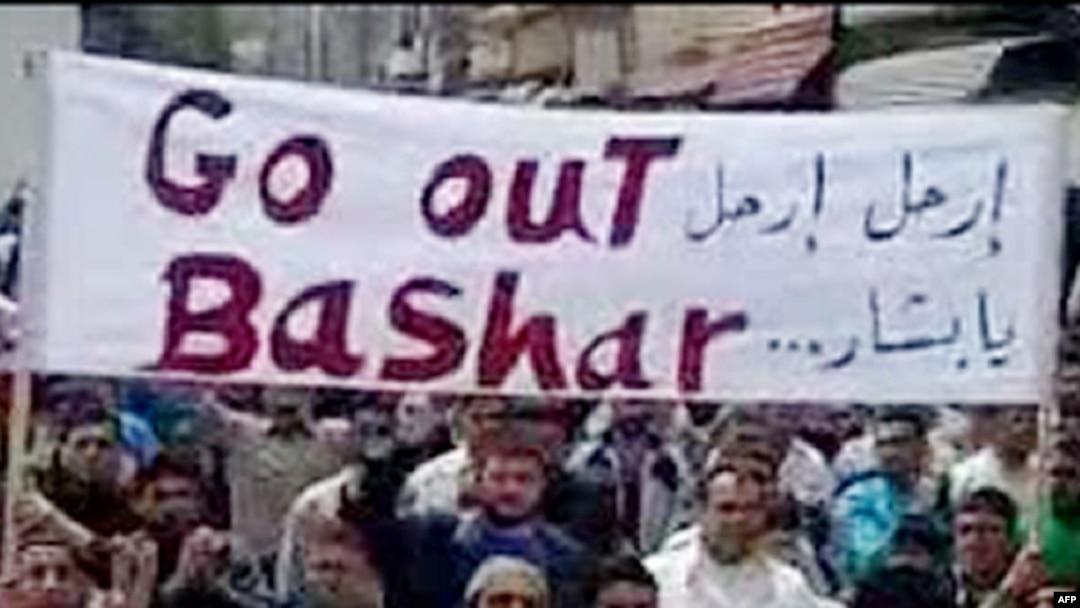 Antigovernment protesters hold a banner that reads in Arabic and English "Go out Bashar" during a pro-democracy demonstration after Friday Prayers in Tal Kalakh on June 10.