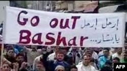 A YouTube video grab shows antigovernment protesters holding a banner that reads in Arabic and English "Go Out Bashar" during a pro-democracy demonstration after Friday Prayers in Tal Kalakh on June 10.