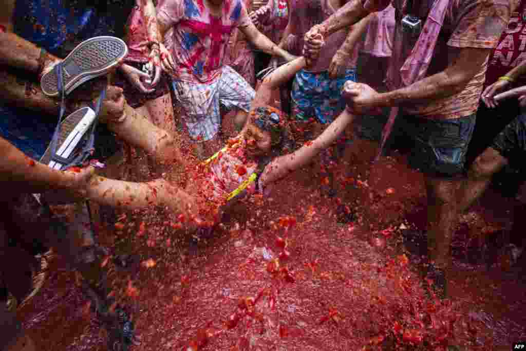 Revelers take part in the annual &quot;Tomatina&quot; festivities in Bunol, near Valencia, Spain. Some 20,000 participants hurled 130 tons of squashed tomatoes at each other, drenching the streets in red. (AFP/Gabriel Gallo)