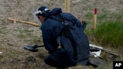 Работник по откриване на мини от неправителствената органзиция за разминиране HALO Trust търси противотанкови и противопехотни мини в Липивка, в покрайнините на Киев, през юни 2022 г.
