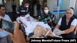 Саҳнаи кӯмак Кӯмак ба навресе, ки дар ҳамлаи мусаллаҳона BRAZIL -- A teenager who was injured during a shooting inside the Raul Brasil State School, is carried on a gurney into a hospital, in Suzano, March 13, 2019