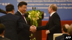 Chinese President Xi Jinping (left) shakes hands with Russian President Vladimir Putin during a ceremony marking the 15th anniversary of the signing of the China-Russia Treaty on Good Neighborliness, Friendship, and Cooperation, in Beijing's Great Hall of the People on June 25.