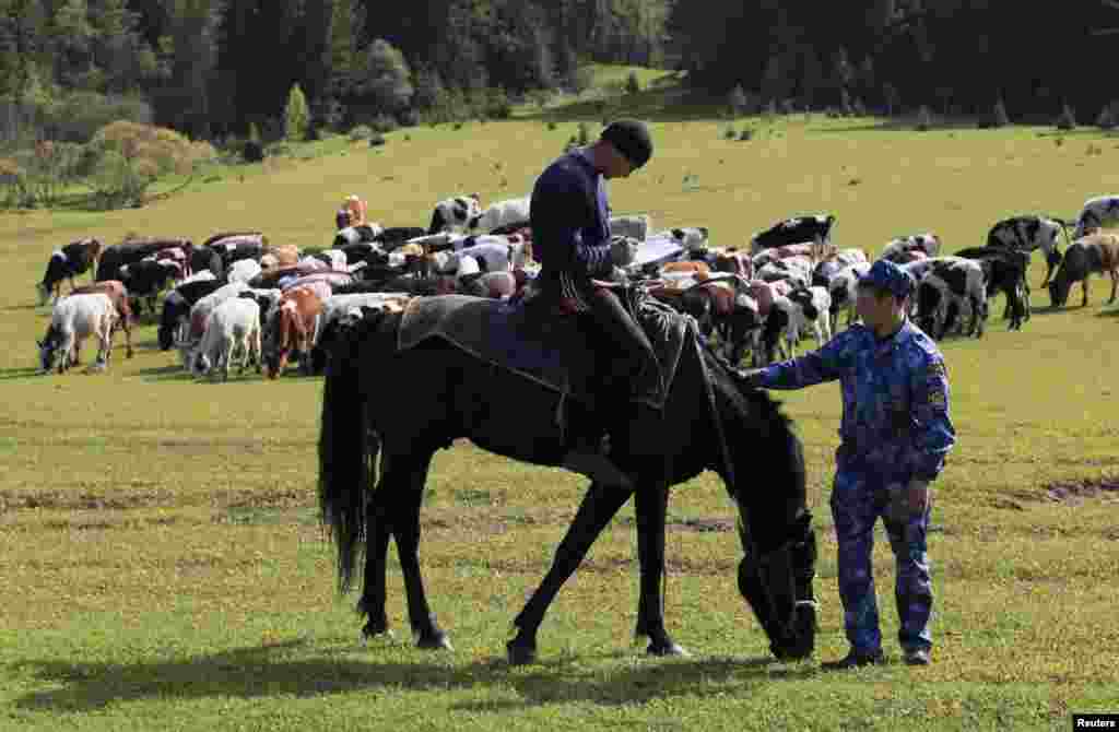 An inmate sits on a horse and signs a document, given by a prison guard during the hourly control, on an agricultural field at a penal colony.